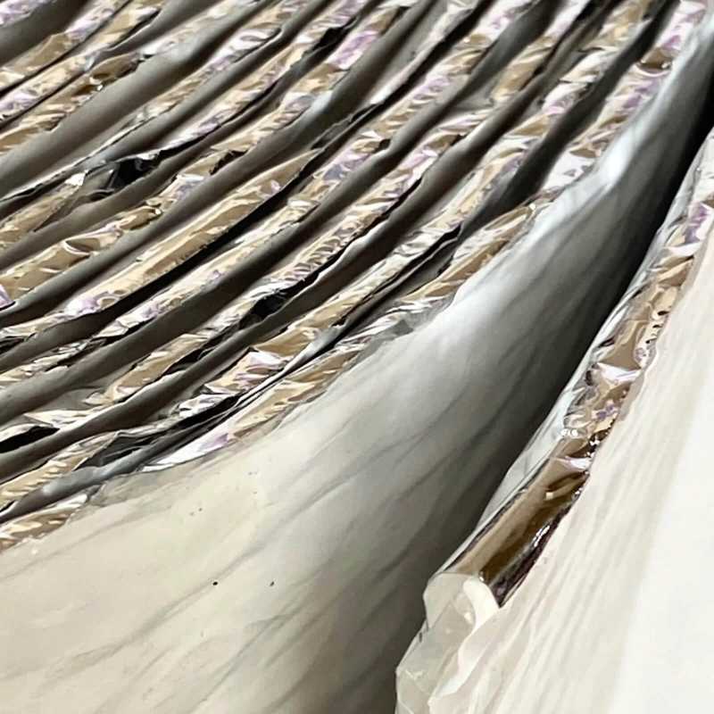 Closeup of ES single bubble insulation with white polyethylene on one side and reflective foil on the other.